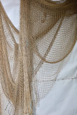 A fishing net hangs on a white wall in a farm. Fishing tackle, net on a farm in the village.