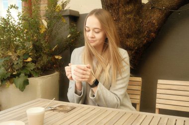 Beautiful girl with a cup of coffee. Cute girl with long hair and a mug of coffee or tea.