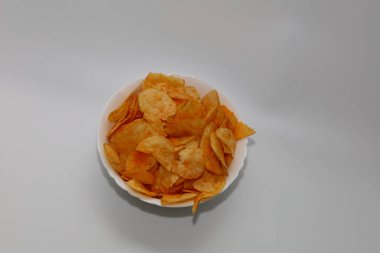 Beyaz arka planda bir tabak çip. Beyaz arka planda baharatlı lezzetli cipslerle dolu beyaz tabak..