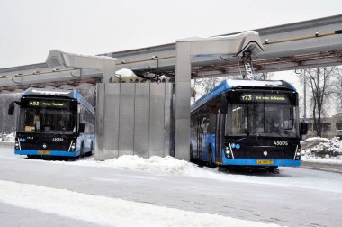 Moskova, Rusya - 30 Ocak 2022: Şarj olurken şarj istasyonunda elektrikli otobüs. Sert kış koşullarında çalışmak.