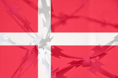 Danimarka ulusal bayrağının bükülmüş dikenli tellerle soyut görüntüsü. Bastırma.