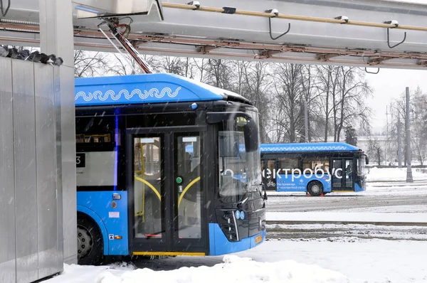 Moskova, Rusya - 30 Ocak 2022: Şarj olurken şarj istasyonunda elektrikli otobüs. Sert kış koşullarında çalış. Kötü çekim koşulları. Kar yağıyor..