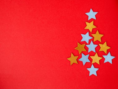 Altın ve gümüşten yapılmış Noel ağacı. Tatil yıldızı şeklinde süsleme. Kırmızı kağıt arka plan. Tebrik kartı poster şablonu. Yaratıcı inceleme konsepti. Düz konum, üst görünüm, kopyalama alanı