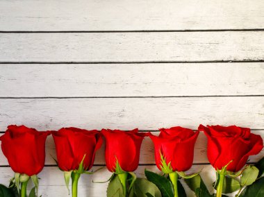 Alttaki kırmızı güllerin sınırı beyaz ahşap masada, düz yerde, üst vew, kopyalama alanı. Sevgililer Günü, düğün, kadınlar, anneler günü ya da doğum günü tatili. Kapat.