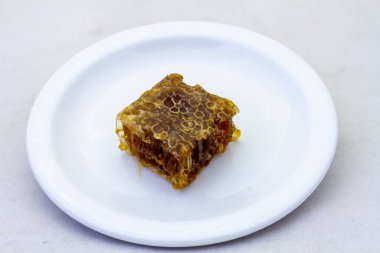 Beyaz seramik bir tabakta saf bal peteği.