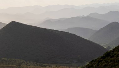 Gün batımına doğru kaybolan tepeleri olan bir vadi.