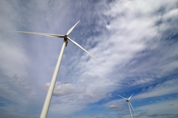 White wind turbine generating electricity on blue sky Royalty Free Stock Images