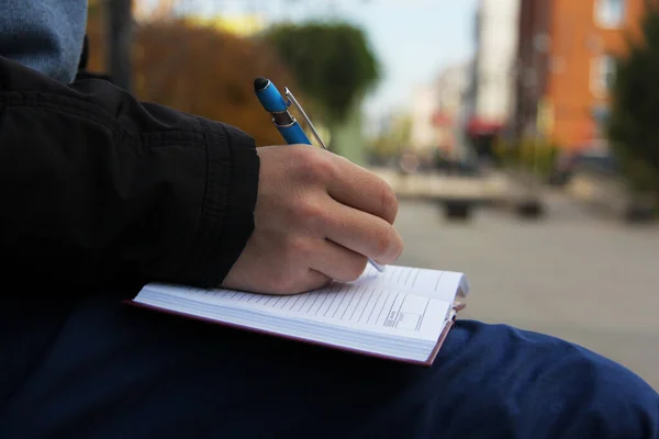 Genç bir adamın elleri şehirde bir defter tutuyor. 