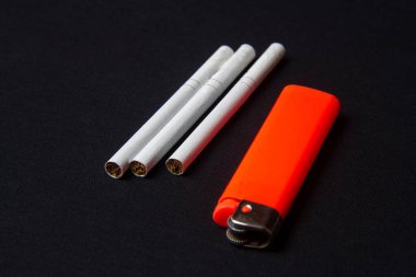 A bright orange lighter and three cigarettes on the table