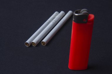A bright orange lighter and three cigarettes on the table
