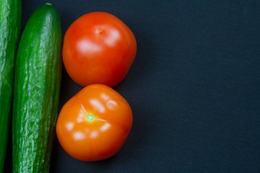Domatesler, salatalıklar ve koyu bir arka plan. Sağlıklı yemek. 