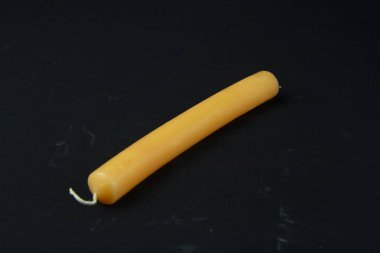 Parlak turuncu bir mum siyah bir bezle bir masanın üzerinde yatıyor.