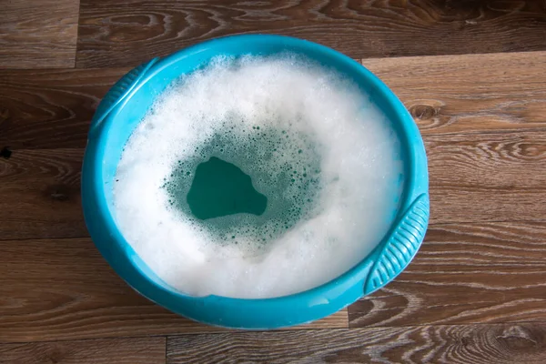 Su dolu plastik bir leğen, evi temizliyor.