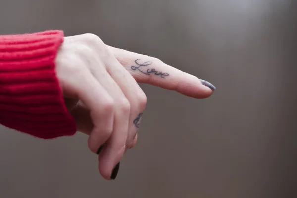 Kvinnlig hand isolerade med en kärlek tatuering på hennes finger — Stockfoto