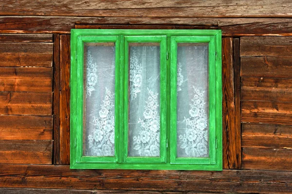 Grüne Fenster eines rustikalen alten Hauses mit Holzwänden Stockbild