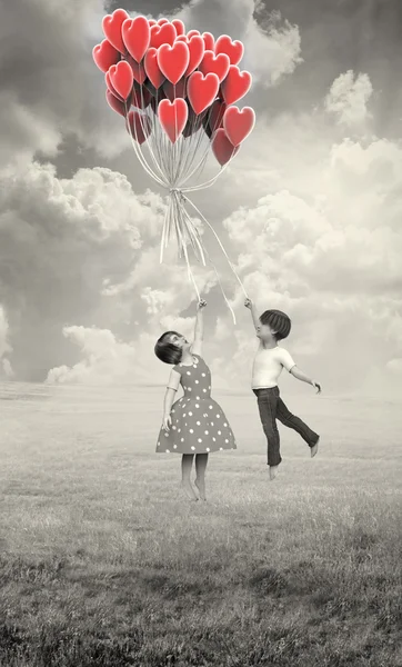 Children flying on balloons heart — Stock Photo, Image