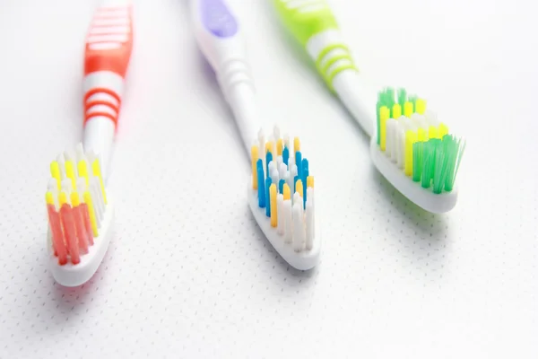 Três escovas de dentes numa prateleira. Feche o tiro de escova de dentes . — Fotografia de Stock