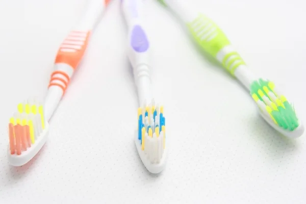Closeup of three toothbrushes of different colors. — Stock Photo, Image