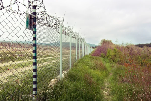 Hek met prikkeldraad. concertina draad boven op een hek beschermen in — Stockfoto