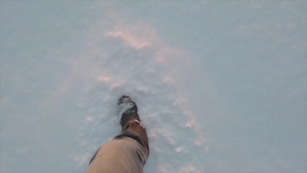 Gambe dell'uomo che cammina sulla neve alla luce del sole. Piedi che camminano nella neve profonda. — Video Stock