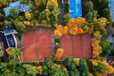 Sonbaharda güzel ağaçlarla çevrili bir tenis kortunun havadan görünüşü