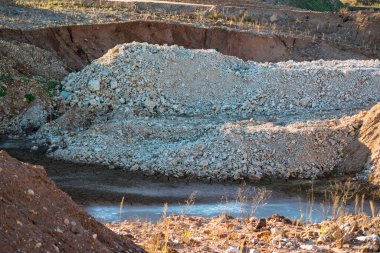 Pit on a stone quarry for the extraction of limestone with a pile of rock