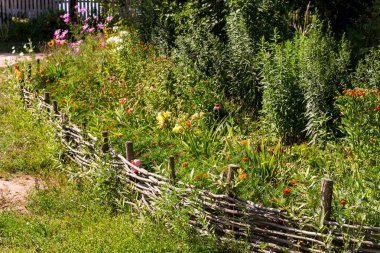 Bahçede çiçeklerle süslü hasırdan çitler