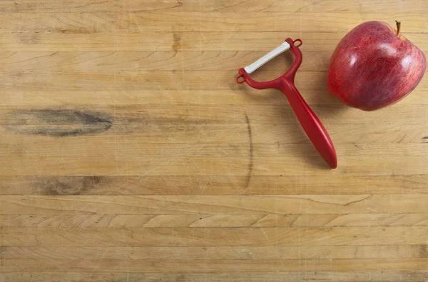 Manzana y pelador en una tabla de cortar —  Fotos de Stock