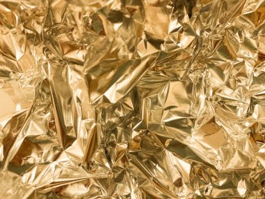Buruşmuş altın folyo dokusu. Parlak şenlikli bir arka plan. Metalleştirilmiş kağıt.