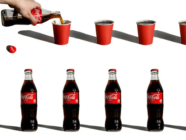 Composição criativa com garrafas repetidas de coca-cola e copos de papel — Fotografia de Stock