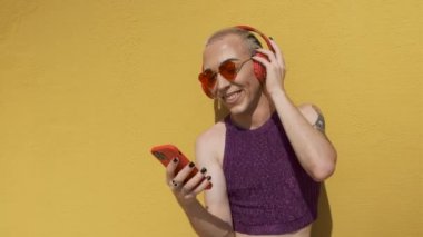 Genç eşcinsel adam kulaklık, akıllı telefon ve müzik kullanıyor.