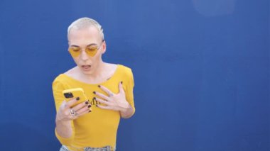 Genç adam, akıllı telefonla sosyal ağları kaydırırken şaşırdı ve gülümsedi - lgtbq konsepti