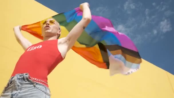 Güneşli bir günde lgtbi bayrağı taşıyan genç bir gay. — Stok video