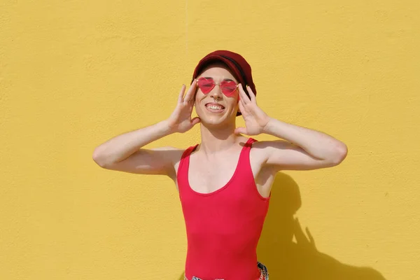 Sonriendo joven persona no binaria posando al aire libre contra una pared amarilla. —  Fotos de Stock