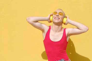 Açık havada kulaklıkla müzik dinlerken gülen ikili olmayan kişi..