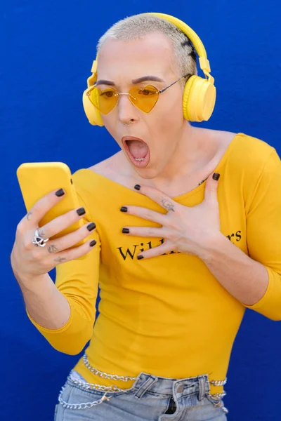 Non-binary young person looking shocked and speechless while checking mobile phone. — Stock Photo, Image