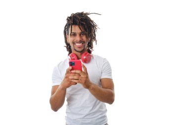 İzole edilmiş bir arka planda dururken cep telefonu kullanan kulaklıklı bir Latin..