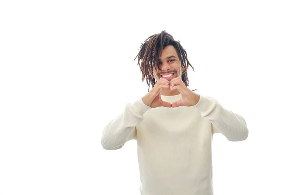 Hombre sonriente haciendo una forma de corazón con las manos mientras está de pie sobre un fondo aislado. —  Fotos de Stock