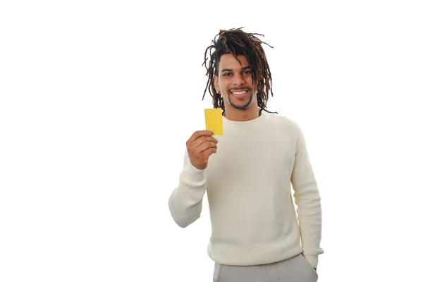 Hombre latino sonriente sosteniendo una tarjeta de crédito mientras está parado sobre un fondo aislado. — Foto de Stock