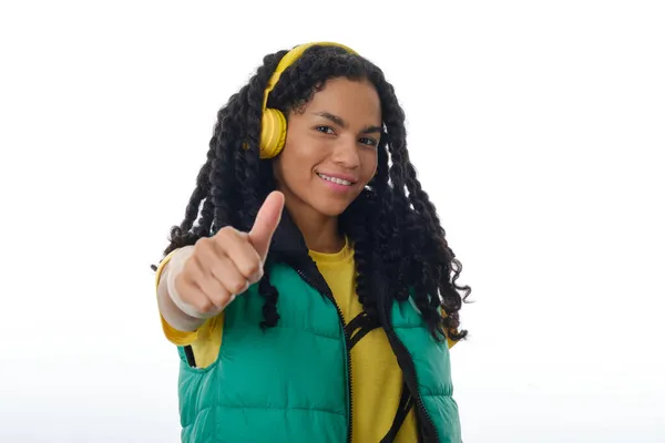 Mujer sonriente mostrando el pulgar hacia arriba mientras escucha música con auriculares. —  Fotos de Stock