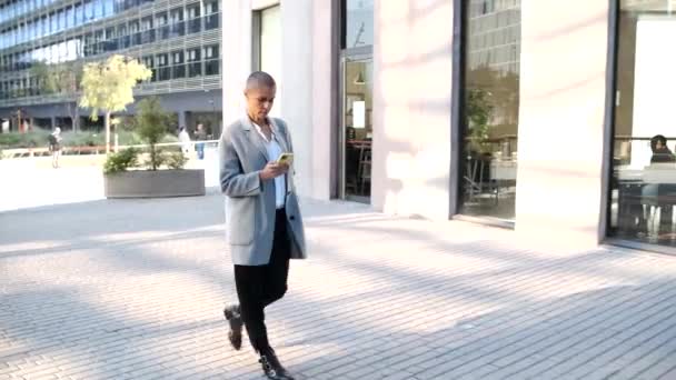 Jong zakenvrouw executive lopen financieel district en met behulp van smartphone — Stockvideo