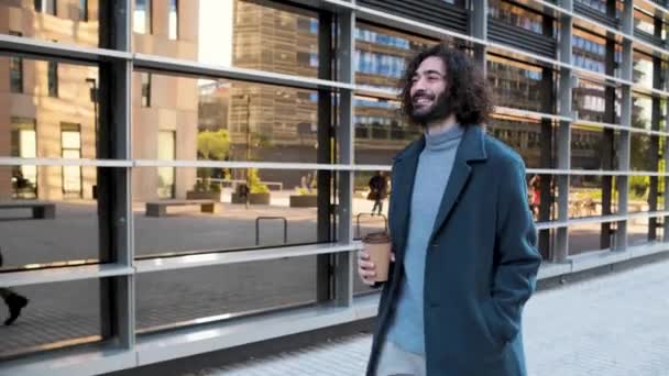 Jonge hipster zakenman glimlachen en wandelen met een koffie in het zakendistrict — Stockvideo