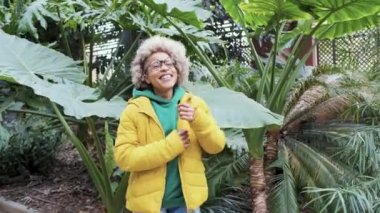 Botanik bahçesinde dans ederken gülümseyen Latin Afrikalı kadın..