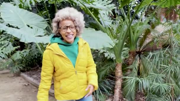 自然の庭で楽しく踊りながらカメラと笑顔を見ながらアフロラテン女性. — ストック動画