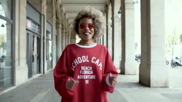 Mulher afro confiante sorrindo enquanto desfruta de uma dança ao ar livre na rua. — Vídeo de Stock