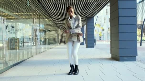 Беззаботная и счастливая деловая женщина танцует на открытом воздухе в финансовом районе. — стоковое видео