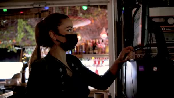 Serveerster met gezichtsmasker plaatst een bestelling voor de klant op een touchscreen tijdens het werken in een restaurant. — Stockvideo