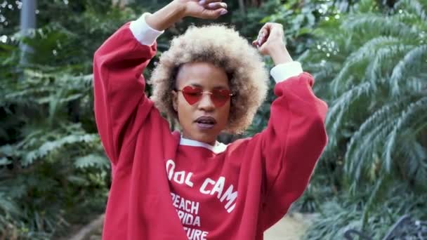 Carefree afro woman enjoys dancing in a natural garden. Slow motion. — Stock Video