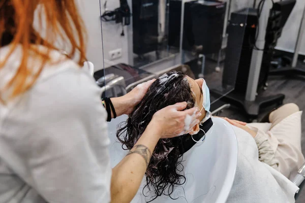 Peluquería profesional lavando el cabello de una clienta mientras trabaja en una peluquería. —  Fotos de Stock