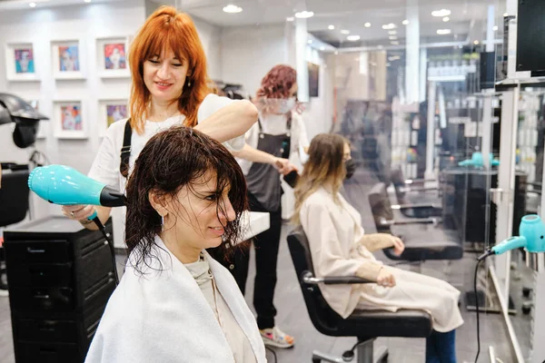 Peluquería seca el cabello de un cliente después de lavarlo en el salón de belleza. —  Fotos de Stock